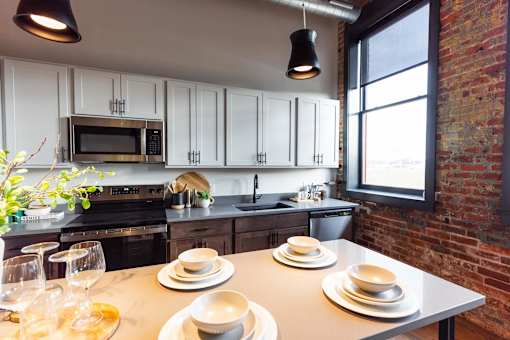 A kitchen with a table set for two with plates and glasses.at Plant 1 Lofts, Iowa   