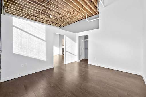 A room with wooden floors and a white wall with a doorway leading to another room.at Plant 1 Lofts, Iowa, 50208