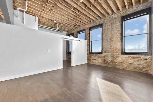A room with wooden floors and a brick wall.at Plant 1 Lofts, N. Newton, IA  