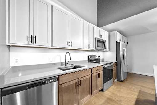 A kitchen with white cabinets and stainless steel appliances.at Plant 1 Lofts, N. Newton Iowa   