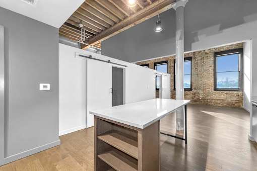 A kitchen with a white countertop and wooden floors.at Plant 1 Lofts, Iowa, 50208