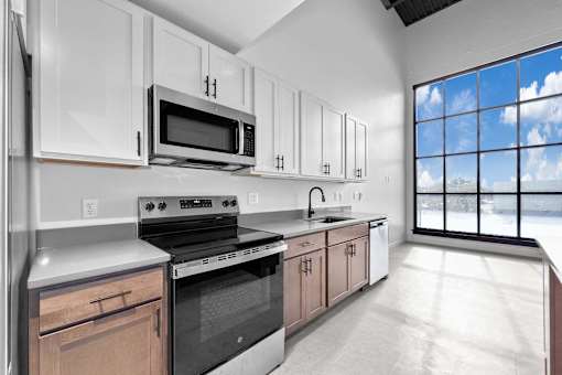 A kitchen with white cabinets and a large window.at Plant 1 Lofts, N. Newton, 50208  