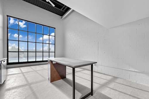 A white room with a table and a window showing a blue sky.at Plant 1 Lofts, N. Newton, 50208  