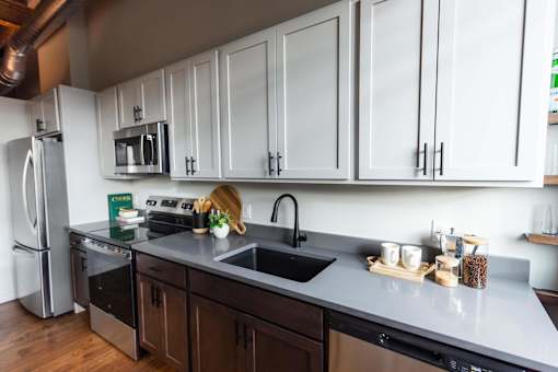 A kitchen with white cabinets and a black sink.at Plant 1 Lofts, N. Newton, IA  