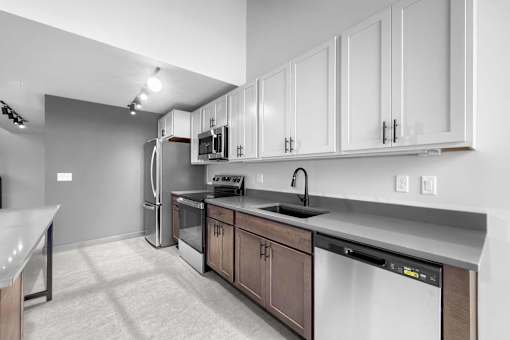 A modern kitchen with white cabinets and stainless steel appliances.at Plant 1 Lofts, Iowa   
