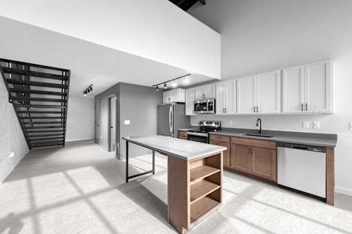 A modern kitchen with a white island and stainless steel appliances.at Plant 1 Lofts, N. Newton, IA  