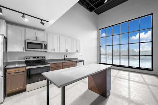 A modern kitchen with a large island and a view of the outdoors.at Plant 1 Lofts, N. Newton, IA  