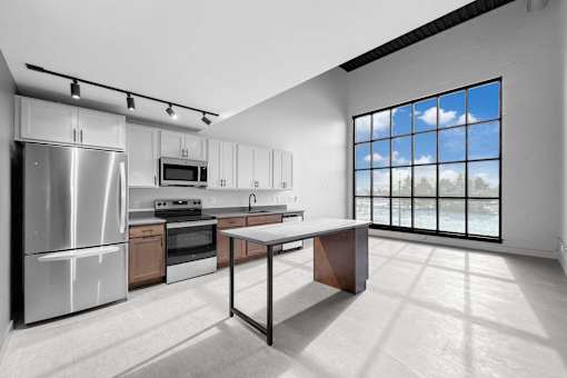 A modern kitchen with a large window overlooking the trees.at Plant 1 Lofts, N. Newton  