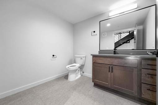 A bathroom with a toilet, vanity, and mirror.at Plant 1 Lofts, Iowa   