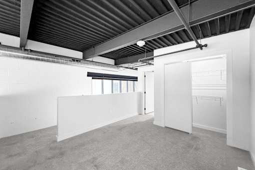 A large, empty room with a carpeted floor and white walls.at Plant 1 Lofts, N. Newton  