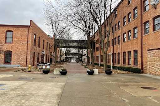 A long brick building with a walkway in front.at Plant 1 Lofts, N. Newton, IA  