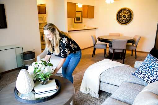 a woman arranging flowers on a coffee table in a living room at Bristol Ridge, Urbandale, IA, 50322
