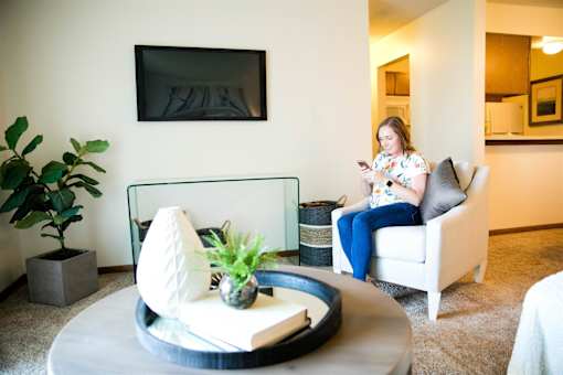 a woman sitting in a chair in a living room looking at her cell phone at Bristol Ridge, Urbandale