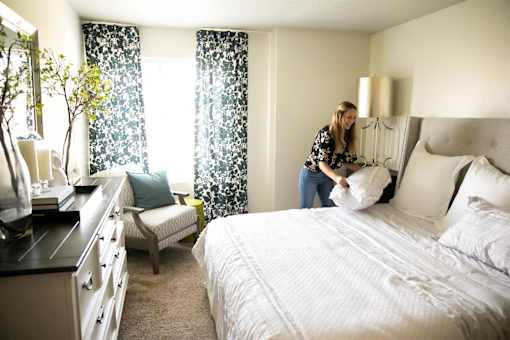 a woman piling pillows on a bed in a master bedroom at Bristol Ridge, Iowa, 50322