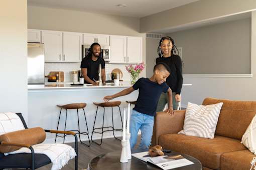 a young boy playing in a living room with his parents at Rialto Townhomes Apartments, Iowa