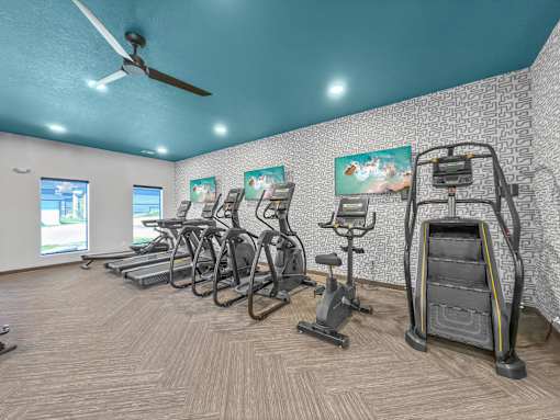 a gym with cardio machines and a ceiling fan at Rialto Townhomes Apartments, Iowa