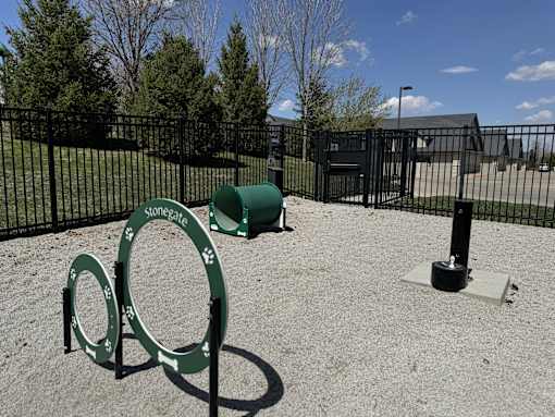 A playground with a green sign that says "Stonegate" and a green barrel.