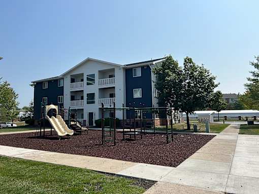 A playground area in front of a blue and white apartment building.