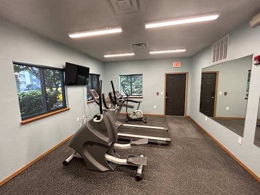 A gym room with a treadmill and exercise bike.