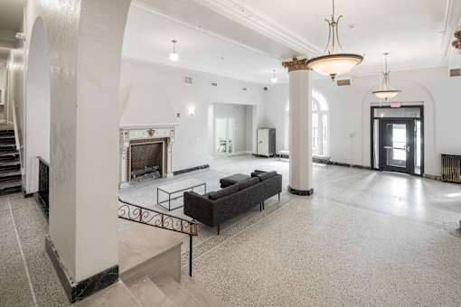 A large, open lobby with a staircase and a fireplace.