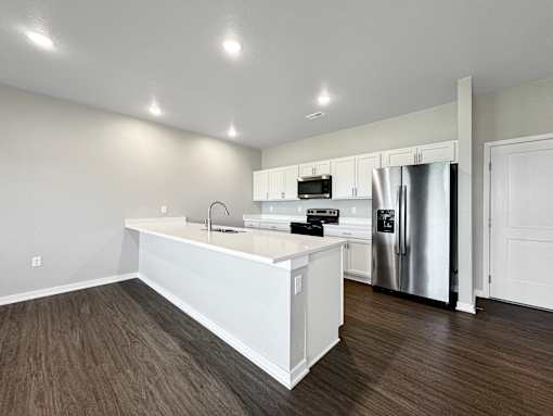 A kitchen with white cabinets and a stainless steel refrigerator.