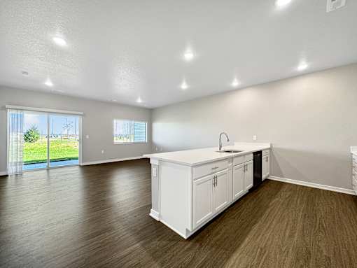 A kitchen with white cabinets and a wooden floor.
