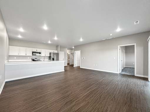 A spacious room with wooden flooring and white walls.