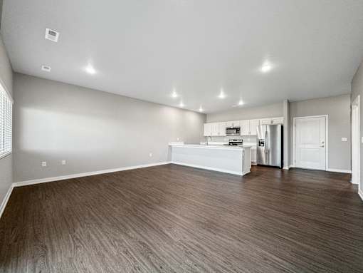 A spacious room with wooden flooring and white walls.