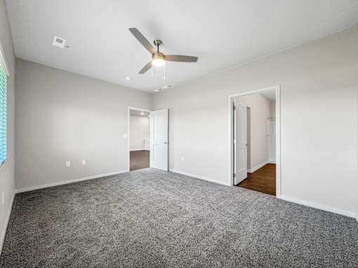 A room with a ceiling fan and carpeted floor.