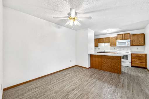 A kitchen with a white ceiling fan and wooden flooring.