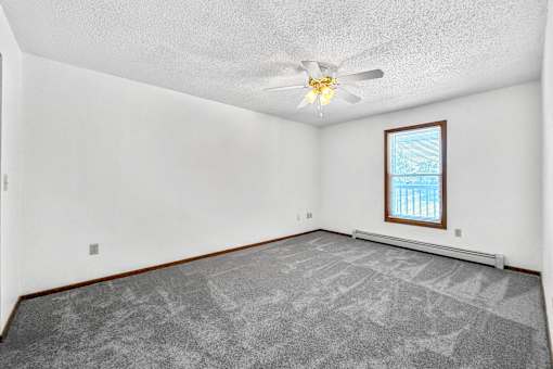 A room with a ceiling fan and a window with blinds.