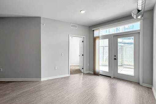 A room with a white door and a window with a view of a building outside.