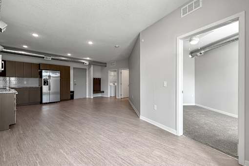 A spacious room with a kitchen area and a large mirror on the wall.
