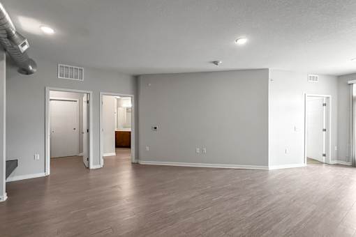 A spacious room with wood flooring and white walls.