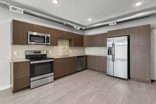 A kitchen with brown cabinets and a stainless steel refrigerator.