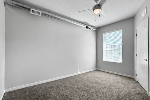 A room with a ceiling fan and a window with blinds.