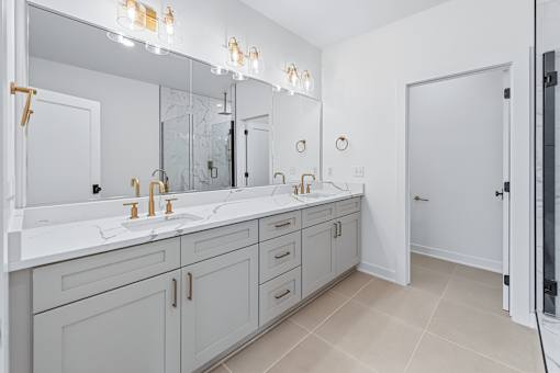 Bathroom vanity with dual sinks and gold fixtures at The Flats at West Glen Apartments, West Des Moines, Iowa