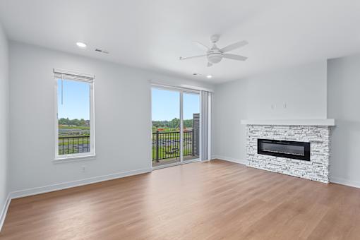 Spacious living room with stone fireplace and balcony access at The Flats at West Glen Apartments, Iowa, 50266