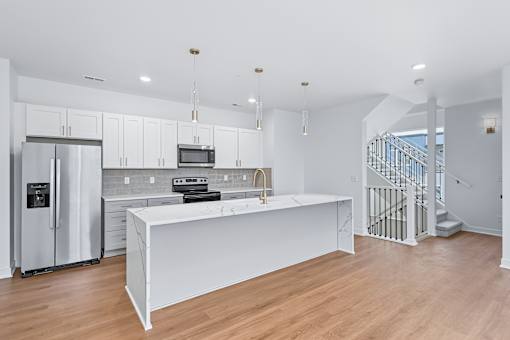 Modern kitchen with island and staircase at The Flats at West Glen Apartments, West Des Moines, IA