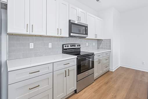 Modern kitchen with white cabinets and stainless appliances at The Flats at West Glen Apartments, West Des Moines, Iowa