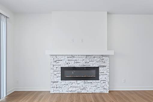 Contemporary living room with stacked stone fireplace at The Flats at West Glen Apartments, Iowa, 50266