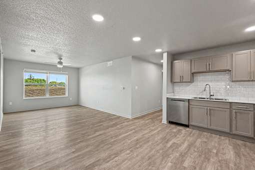 A kitchen area with wooden floors and a window showing a view of a field.