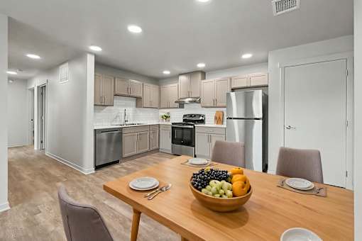 A modern kitchen with a dining table set with a bowl of fruit.