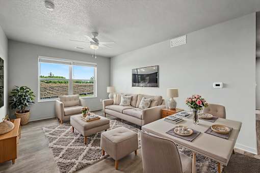 A living room with a grey couch, a coffee table, and a flat screen TV mounted on the wall.
