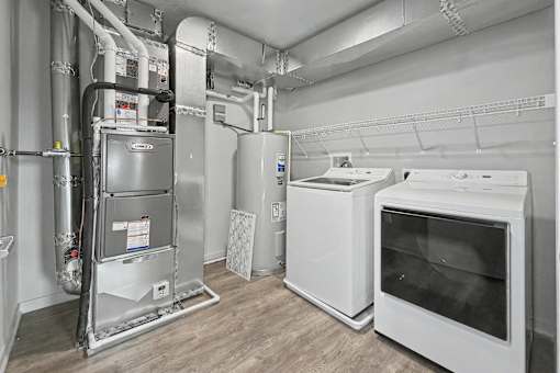 A clean, empty room with a white oven, dryer, and a refrigerator.