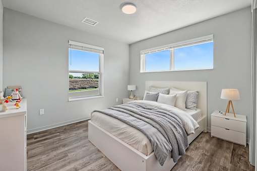 A bedroom with a large bed, a nightstand, and a window overlooking a field.