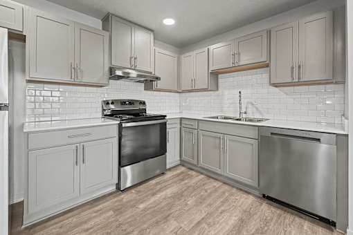 A modern kitchen with stainless steel appliances and wooden flooring.