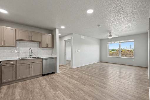 A kitchen with wooden floors and a window showing a beach scene.