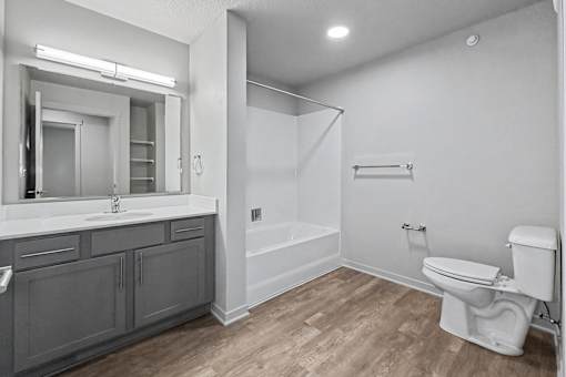 A white toilet sits in a bathroom with a walk-in shower.