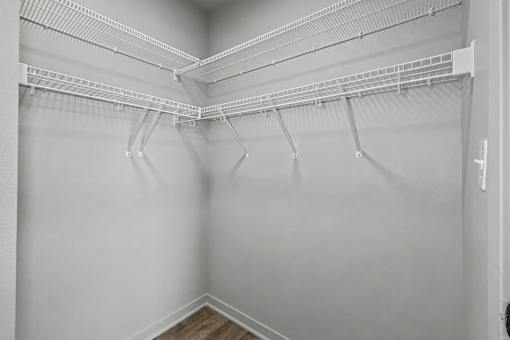 Empty white closet with shelves and hooks.